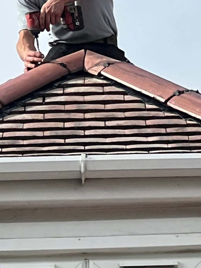 This is a photo of one of the operatives of Huntingdon Roofing Repairs installing new ridge tiles